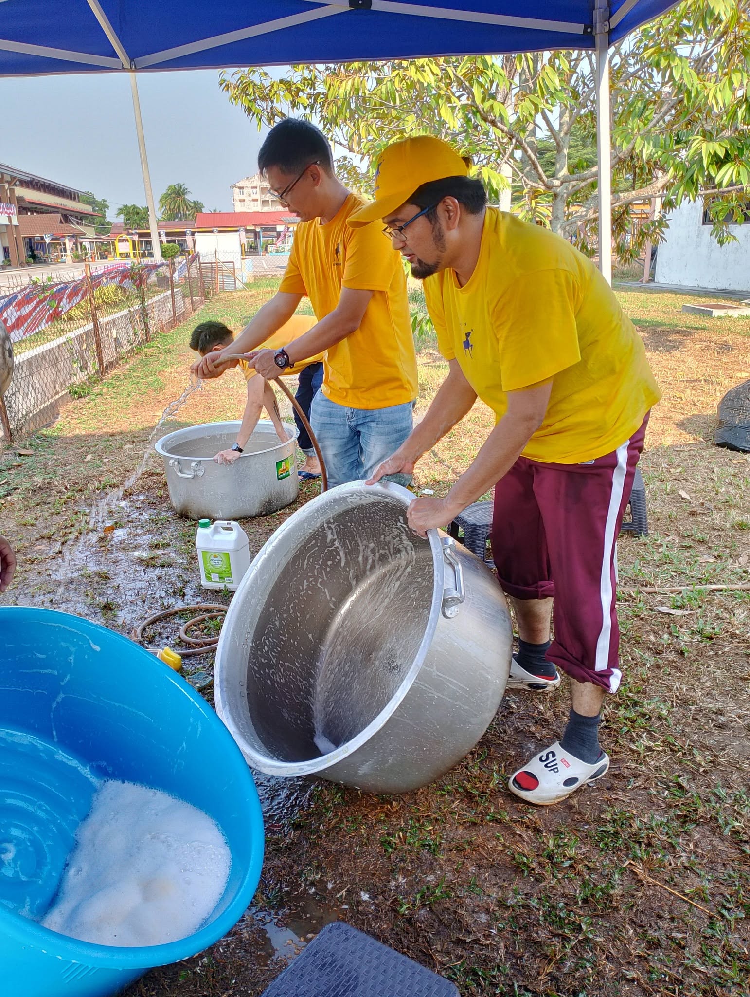 Aman Akil dan ahli pasukan membilas periuk besar di ruang mencuci peralatan kenduri.