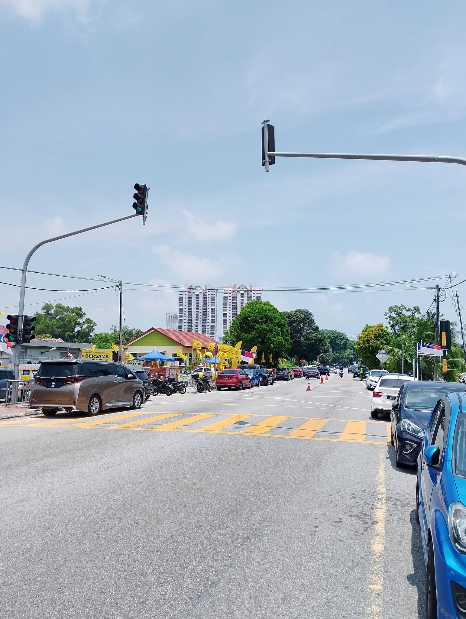 Suasana jalan berdekatan lokasi kenduri dengan khemah biru dan bendera BERSAMA.