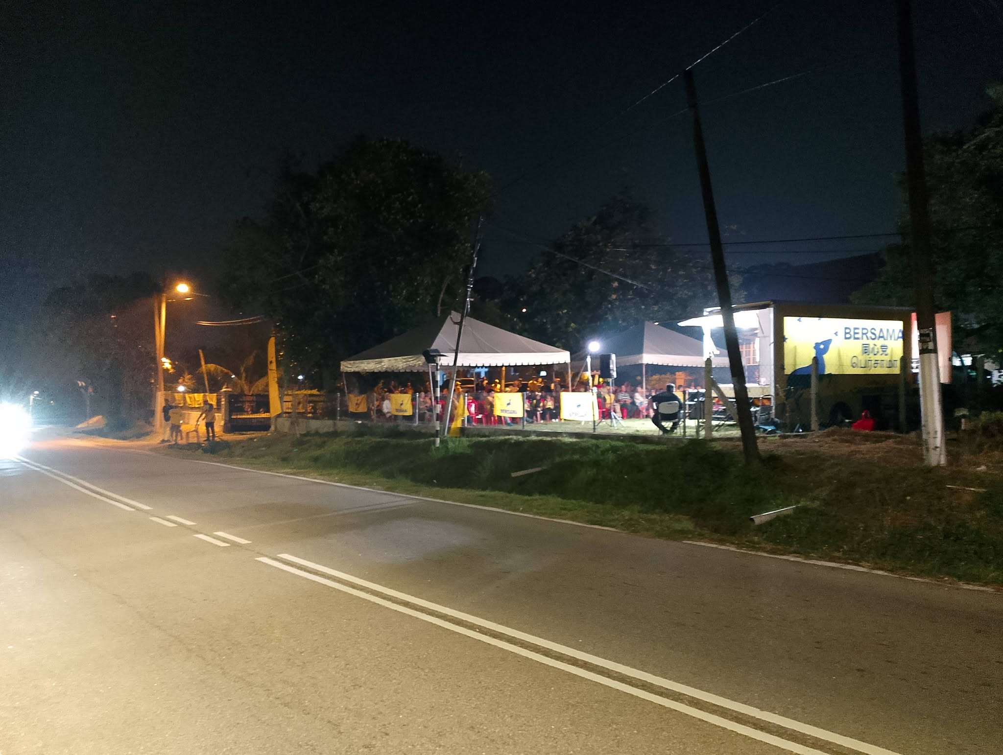 Pandangan lokasi ceramah pada waktu malam dengan pentas trak dan khemah hadirin di tepi jalan.