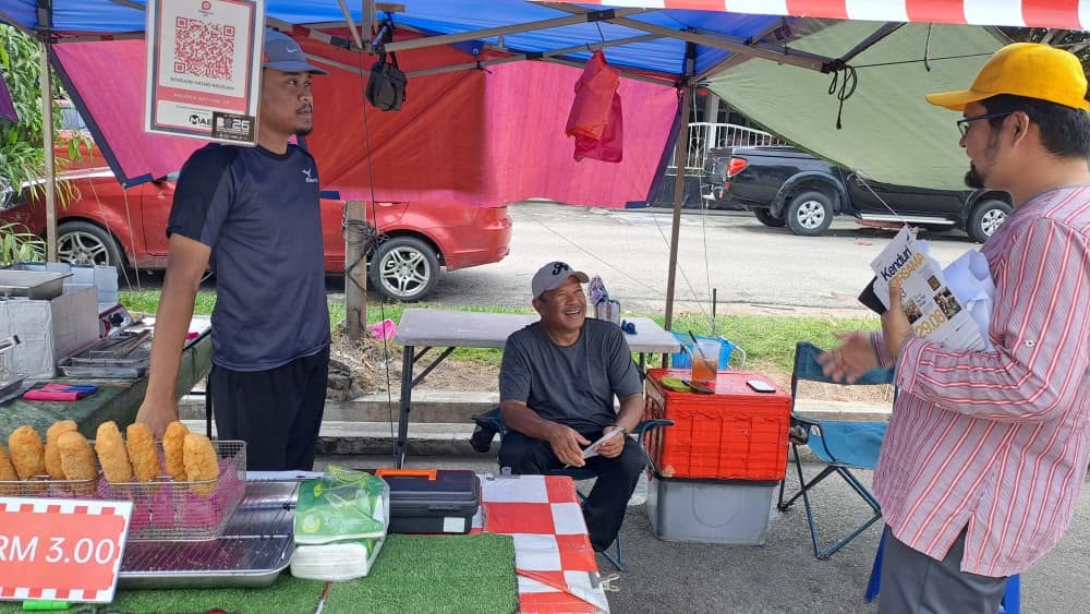 Aman Akil berbual dengan warga setempat di sebuah gerai sambil menyampaikan jemputan Kenduri BERSAMA #3.