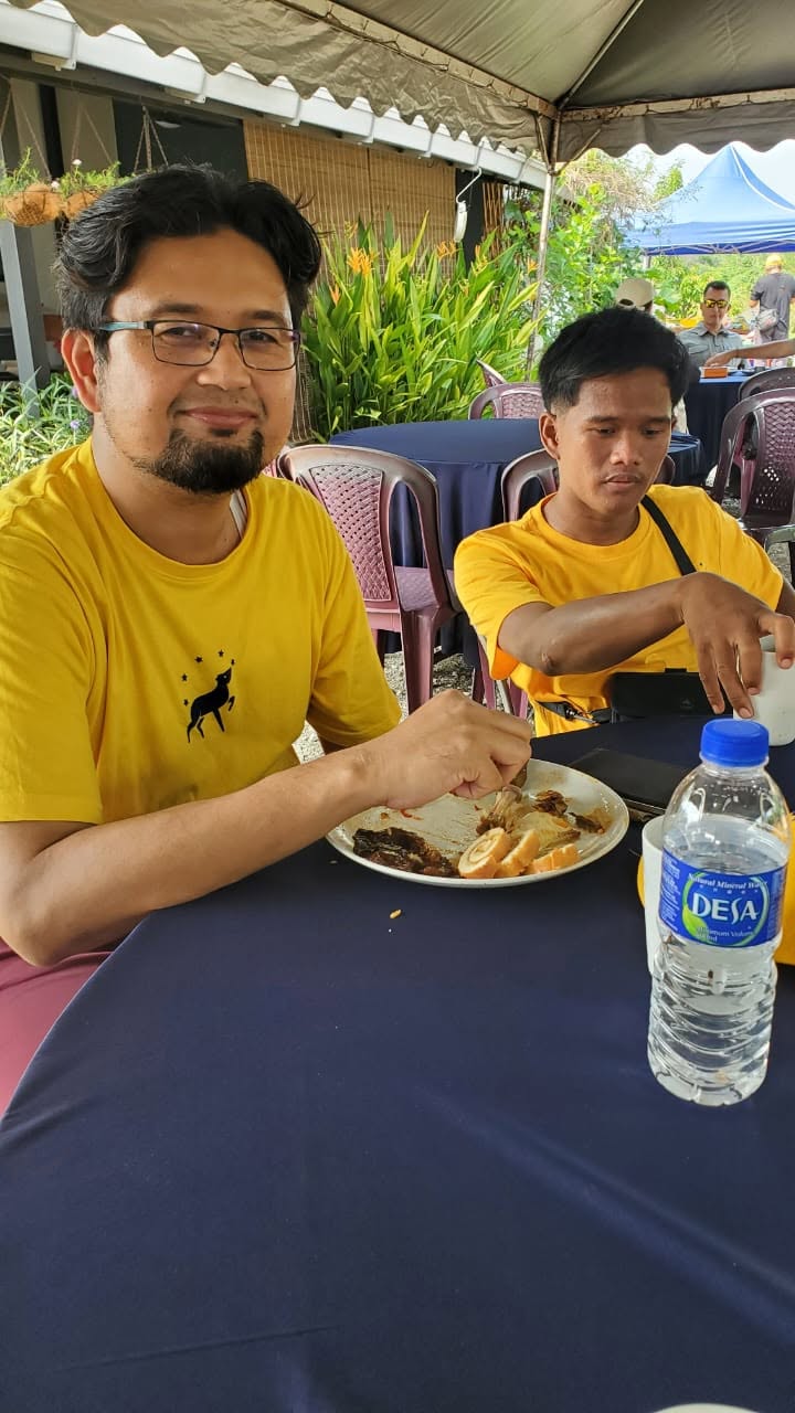 Aman Akil duduk bersama seorang peserta di meja makan semasa kenduri.