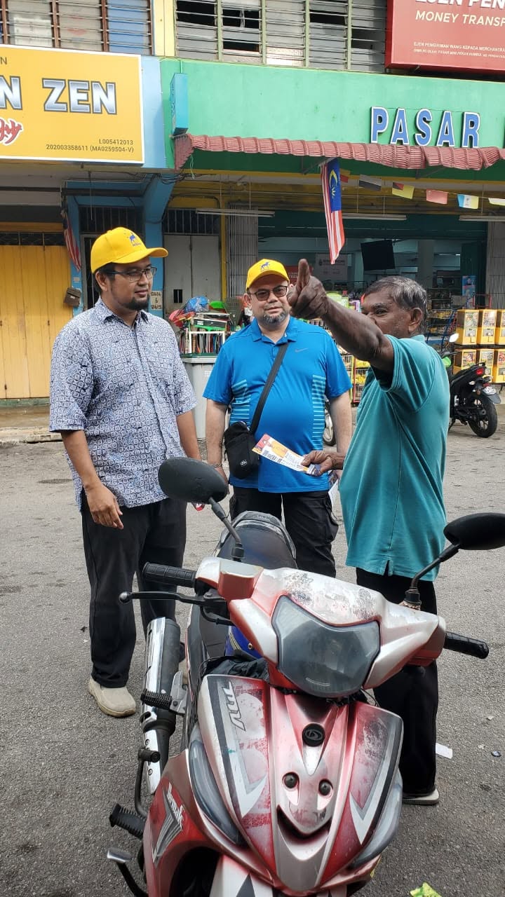 Aman Akil dan pasukan berbual dengan seorang warga setempat di tepi motosikal.