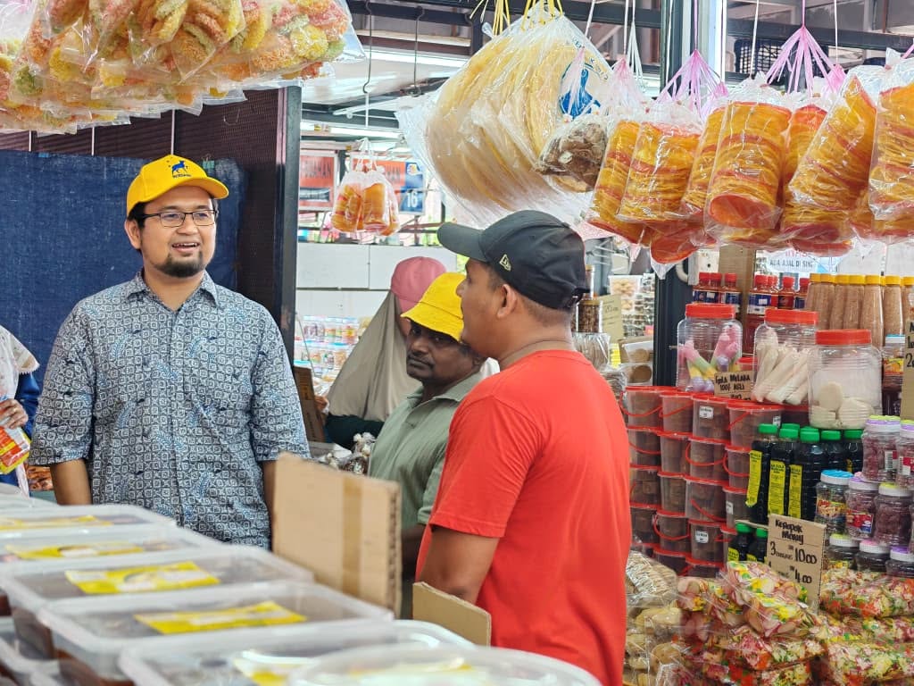Aman Akil berbual dengan peniaga di hadapan barangan makanan yang dipamerkan.